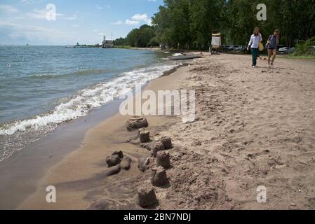 Toronto, Ontario / Canada - August 19, 2017: Two women walking at Cherry Beach with sandcastle in the foreground. Stock Photo