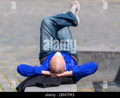 Dresden, Germany. 13th May, 2020. A man lies on a wall on Neumarkt and has pulled his breathing mask on his forehead. Credit: Robert Michael/dpa-Zentralbild/dpa/Alamy Live News Stock Photo