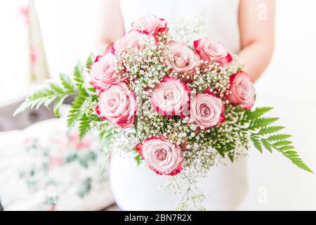 Bride Holding Fresh Pink Roses, Gypsophila and Fern Bouquet Stock Photo