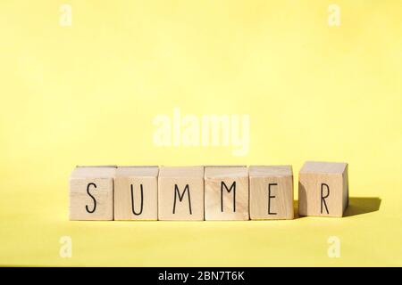 Wooden cubes with the word Summer on Yellow background, colorful bright summer concept . Cheerful Stock Photo