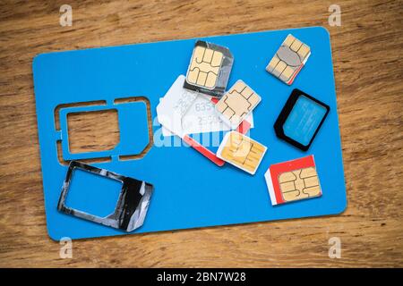 Close up of sim cards on wood grain background; Travellers can trade out sim cards by country to stay in communication while keeping costs low. Stock Photo
