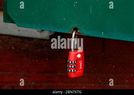 A red 3 digit combination number lock on a green post box. Stock Photo
