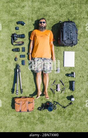 flat lay of a photographer and all his equipment of cameras, lenses, backpack, tripod on a grass background, top view Stock Photo