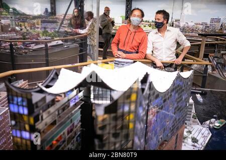 Hamburg, Germany. 13th May, 2020. Frederik (r) and Gerrit Braun, founder and managing director of the Miniatur Wunderland, stand behind the model of the Elbphilharmonie Concert Hall with mouthguards during a test run with 200 in the facility. After weeks of closure due to the corona pandemic, the model railway facility in Hamburg wants to slowly reopen for visitors. Railway fans can visit the world's largest model railway again from May 20. Credit: Christian Charisius/dpa/Alamy Live News