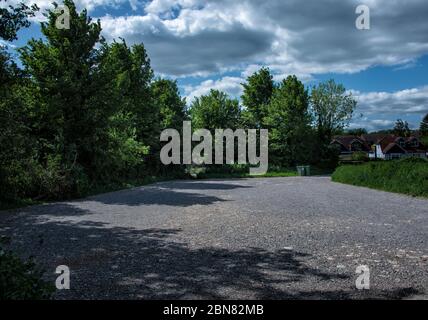 An empty car park next to a dog walkers field and playground.  This has been closed to cars due to coronavirus. Stock Photo