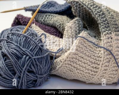 Close up wool colored knitting gold needle, kniting woolen texture, grey ball of woolen yarn with knitted parts of a sweater Stock Photo