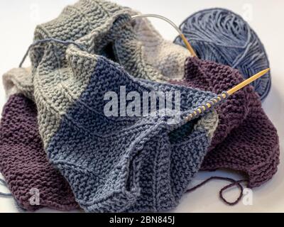 Close up wool colored knitting gold needle, kniting woolen texture, grey ball of woolen yarn with knitted parts of a sweater Stock Photo