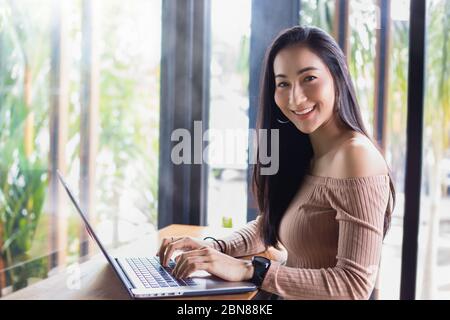 Asian businesswomen are using notebook computers for working from home.She is smile happy and enjoys working. Stock Photo