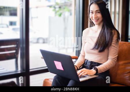 Asian businesswomen are using notebook computers for working from home.She is smile happy and enjoys working. Stock Photo