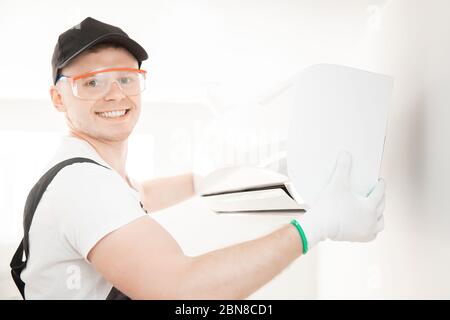 Technician man worker repairing and installs air conditioner on white wall Stock Photo