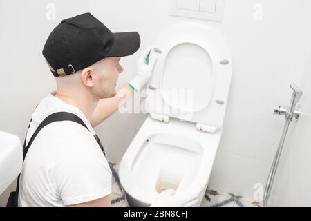 Plumber installing toilet bowl in restroom, work in bathroom Stock Photo
