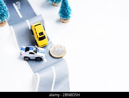 Cars accident on rough road. Expensive insurance. Incident. Toy models and coin 1 euro on duct tape. Slippery or rough road. Insurance. Incident Stock Photo