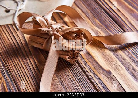 cinnamon sticks tied with brown ribbon on wooden background Stock Photo