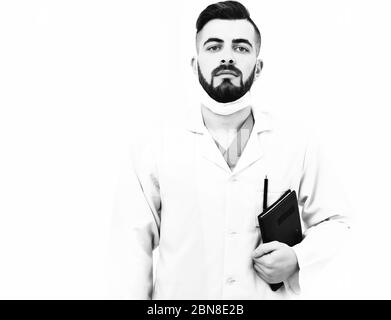 Doctor with beard holds notebook with history of present illness. Treatment and ambulance services concept. Man with confident face in white medical coat. Surgeon in mask isolated on white background Stock Photo