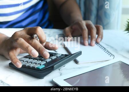 young man use calculator and writing on notepad at home office. Stock Photo