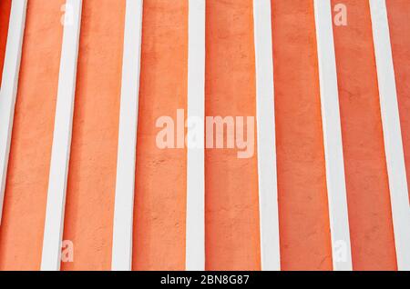 Textured wall of red orange with white relief stripes Stock Photo