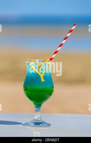 Colorful cocktail drink in glass at beach on sunny day Stock Photo
