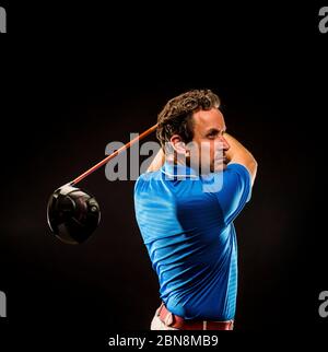 Portrait of a golf player perfecting the swing isolated on dark background Stock Photo