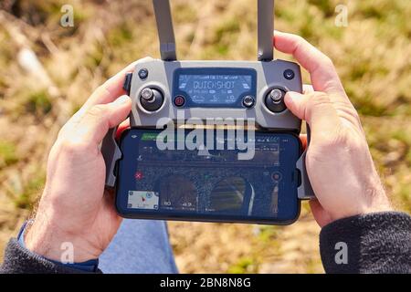 Close up mans hands holding a drones remote controller. A aerial shoot of a bridge is on the screen of smartphone. Real footage concept. Liberec Stock Photo