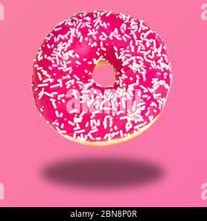 Pink donut with colorful sprinkles on pastel pink background. Sweet donuts. Stock Photo