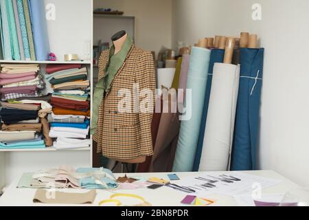 Image of model of stylish jacket on mannequin in the workshop with fabric rolls in the background Stock Photo