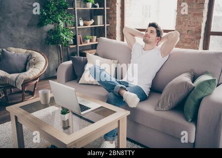 Portrait of his he nice attractive muscular dreamy guy sitting on divan resting pause break working remotely at modern industrial loft interior style Stock Photo
