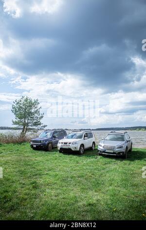 three off road suv cars standing at lake beach Stock Photo