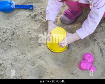 Little Girl Playing in Sandbox with Colorful Plastic Toys Stock Photo