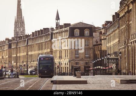 BORDEAUX, FRANCE - 19 JANUARY, 2017 : Tram is passing by downtown, Place de la Bourse with St. Michel church on the back Stock Photo