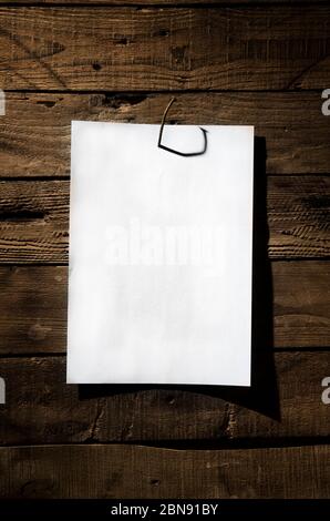 White sheet of paper nailed to a rusty nail a wooden wall. Stock Photo