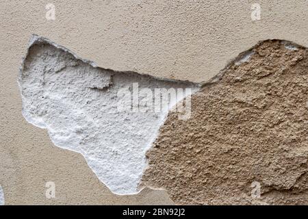 Destroyed weathered bonded plaster background. Texture of the old damaged wall with broken cracked plaster. The ruined aged building surface. Devastat Stock Photo