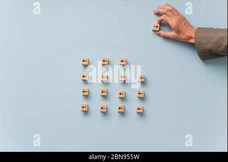 Realizing your own potentials - woman taking a wooden cube with arrow on it out of the group of the others and turning it the other way. Stock Photo