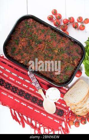 Traditional Romanian dish named 'Varza a la Cluj' made from stewed cabbage, tomato paste and minced meat, rice and dill, red napkin, salad and tomatoe Stock Photo