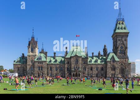 A big group of people doing a free open air yoga class in Ottawa in front of the parlament in Canada Stock Photo