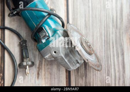 Old grinder laying on the wooden background. Flat lay view of the electric tool Stock Photo