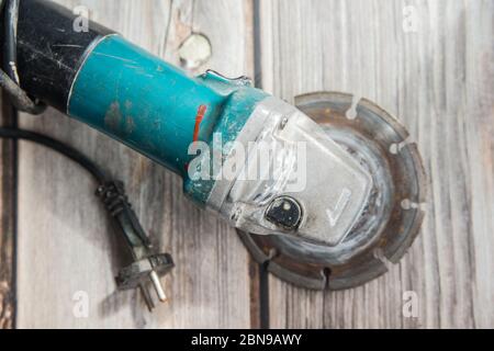 Old grinder laying on the wooden background. Flat lay view of the electric tool Stock Photo