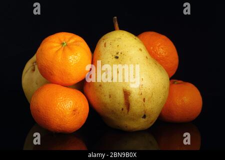 fruits on black background. four tangerines and pear on a black background. Stock Photo