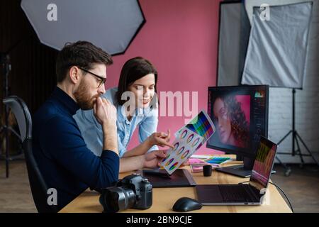 Partners discussing at work. Professional photographer and retoucher. Retouching images. Teamwork in a professional photo studio Stock Photo