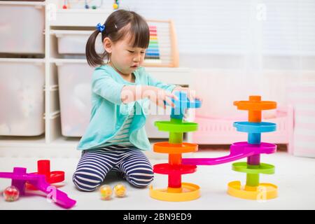 toddler girl play marble run game at gome agianst white background Stock Photo