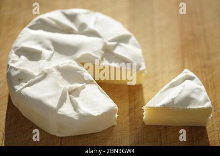 Whole camembert cheese and one slice on a wooden table Stock Photo