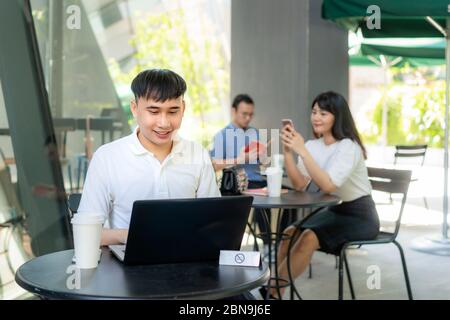 Asian young man and woman sitting one person per one table for distance of 6 feet distance protect from COVID-19 viruses for social distancing for inf Stock Photo
