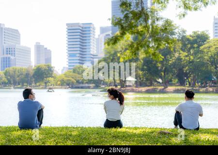 Asian young three man and woman talking and relaxing with they friend and wearing mask sitting distance of 6 feet distance protect from COVID-19 virus Stock Photo