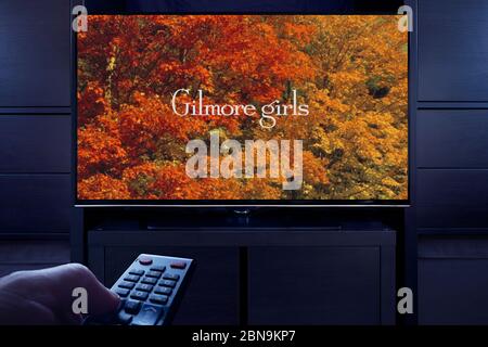 A man points a TV remote at the television which displays the Gilmore Girls main title screen (Editorial use only). Stock Photo