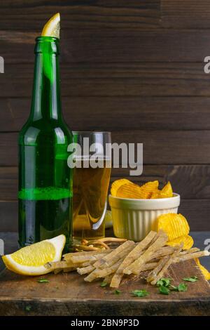Dried salted tuna elite snack with beer, lemon and potato chips on dark wooden board. Snack on fish with beer. Front views, close-up Stock Photo