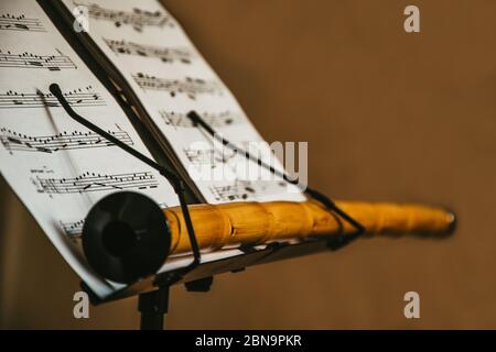 an oriental musical instrument Ney, stays on the music sheet stand with notes, isolated, mystic scene, traditional turkish music materials, closeup Stock Photo
