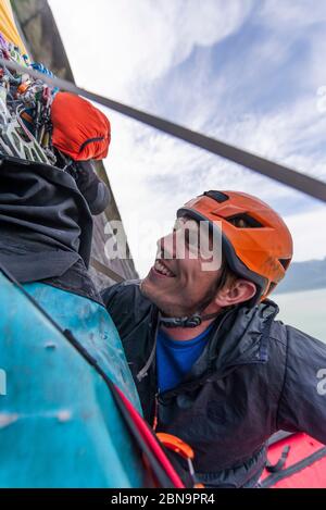 Climber smiling and looking up with climbing helmet to gear hanging Stock Photo