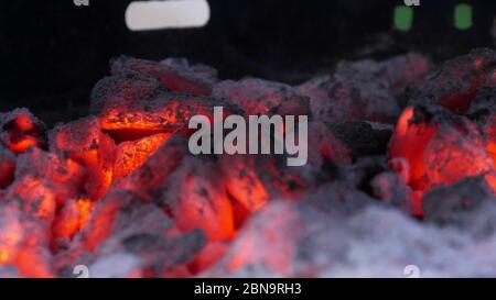 Close view at a glowing charcoal and flame in the barbecue grill. Shallow depth of field. Stock Photo