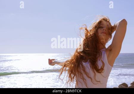 Red haired woman on windy beach Stock Photo