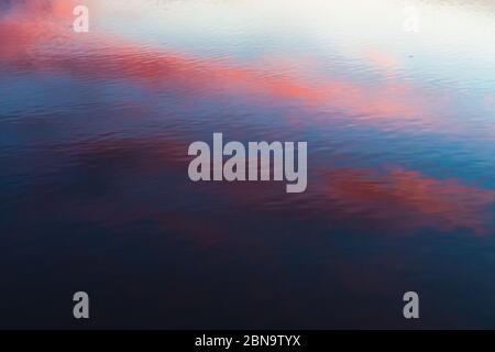 pink orange and blue contrast reflection of sunset on rippled water Stock Photo