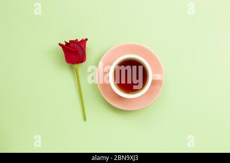 Cup of black tea with red rose on light green background. Flat lay, top view, copy space Stock Photo